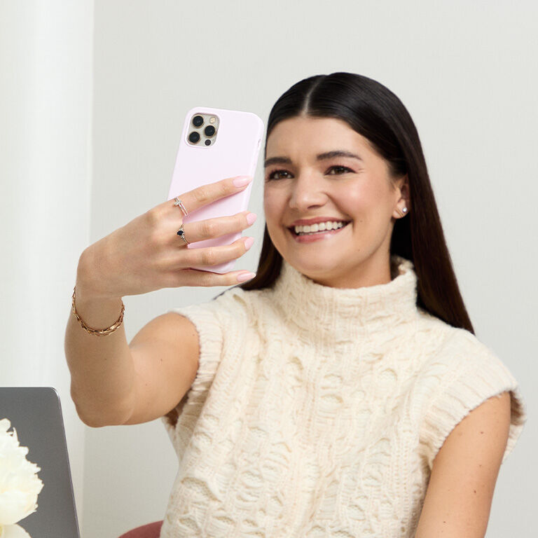 Mujer sonriendo mientras usa en su tel&eacute;fono la herramienta de IA Tu Base Ideal