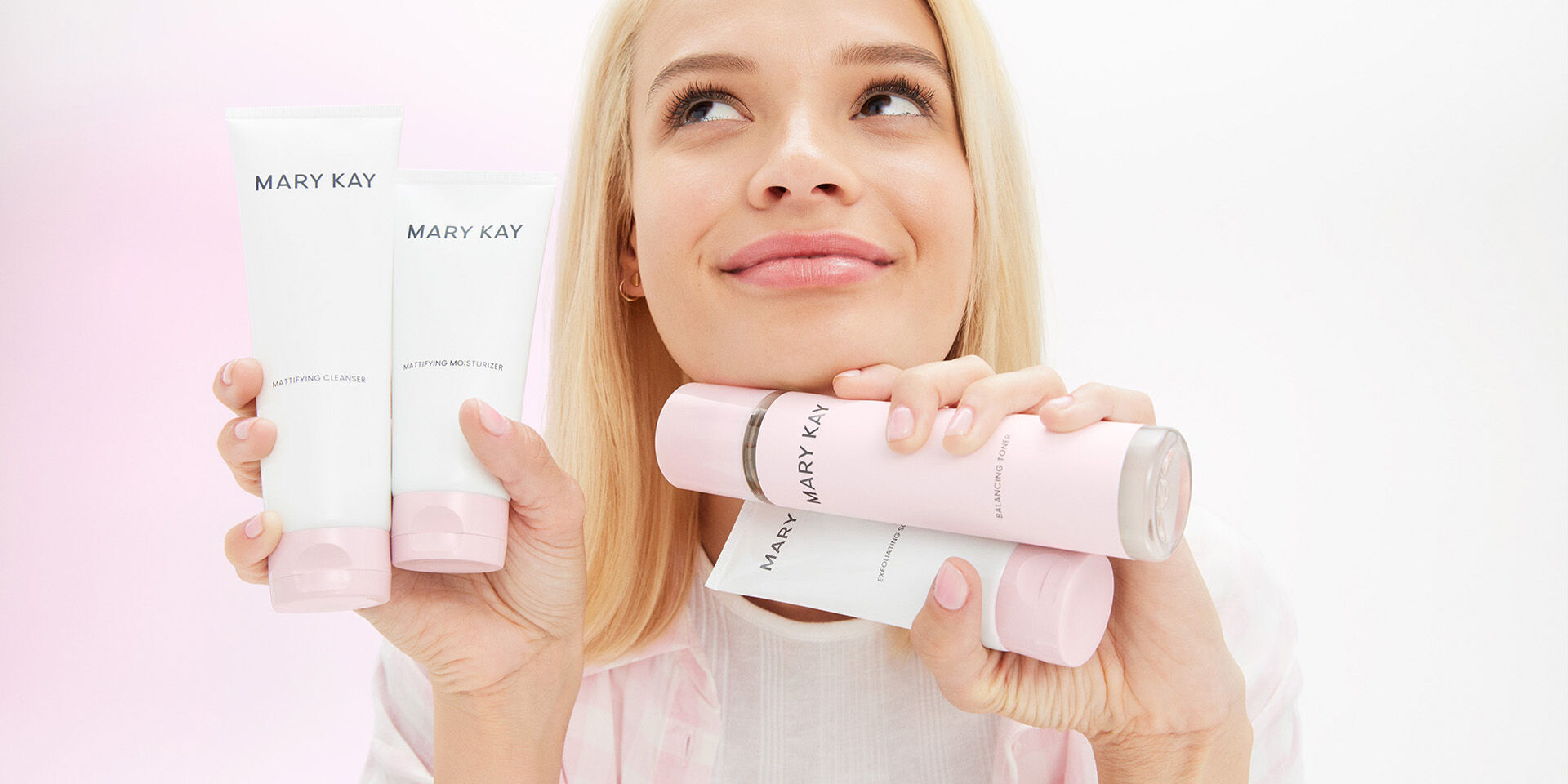 Modelo rubia sosteniendo productos de la Rutina de Cuidado de la Piel Mary Kay&reg; y sonriendo