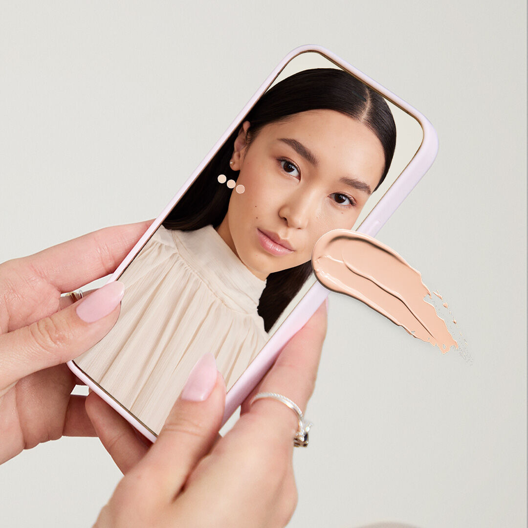 Manos de tono de piel claro sosteniendo un celular que muestra la herramienta Mary Kay Tu Base Ideal.