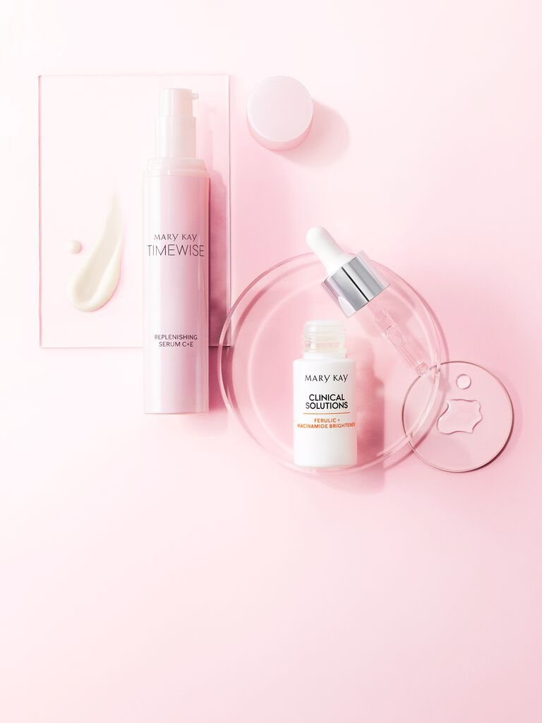 Mary Kay Timewise Replenishing Serum and Clinical Solutions brightener on pink background.