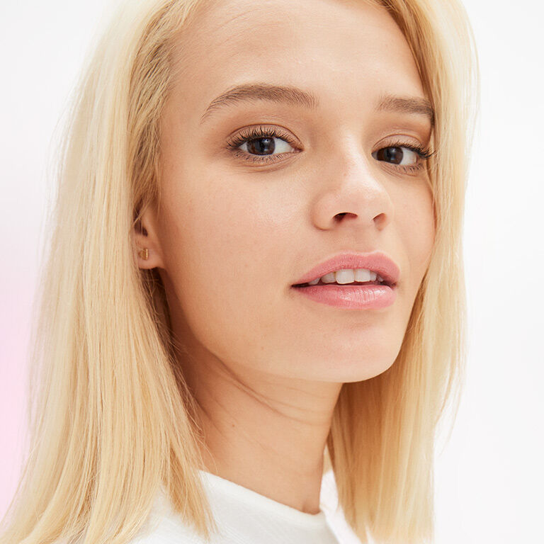 Mujer rubia con un tono de piel media usando maquillaje natural.