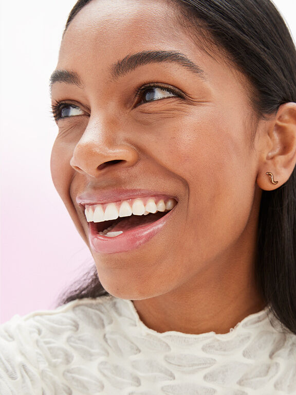 Mujer con tono de piel morena y cabello oscuro, usando maquillaje natural y sonriendo.