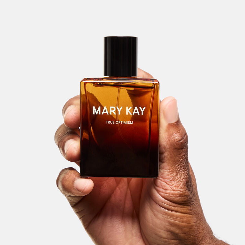 Mary Kay True Optimism Eau de Parfum surrounded by fragrance note ingredients against stone background
