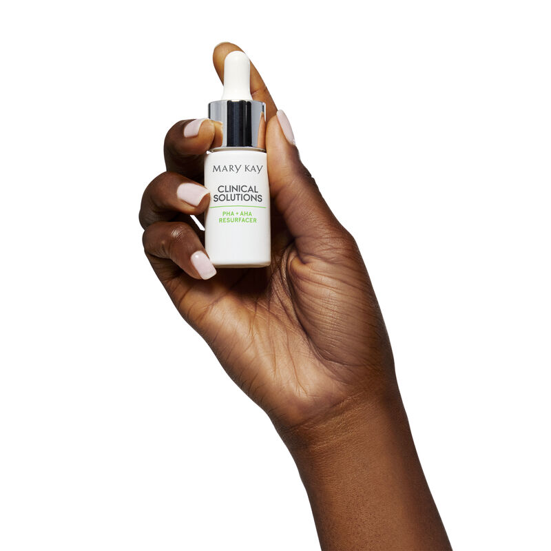 Hand holding dropper and bottle of Mary Kay Clinical Solutions HA + AHA Resurfacer