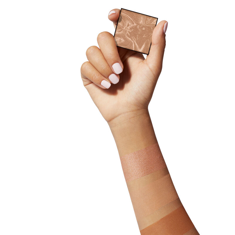 Medium-skinned hand holding limited-edition Mary Kay Illuminating Bronzer