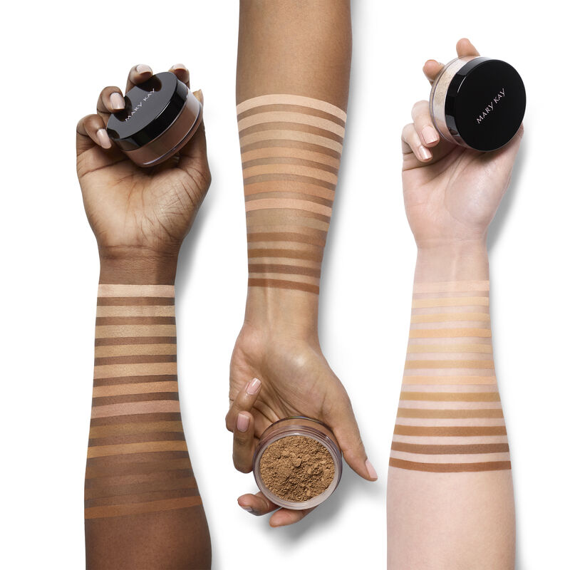 An ivory, beige and bronze arm with shade swatches of all of the Mary Kay Silky Setting Powder shades with hands holding product containers.