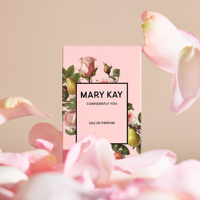 The Mary Kay&reg; Confidently You&trade; light pink box with roses and pears on it appears surrounded by falling petals. 