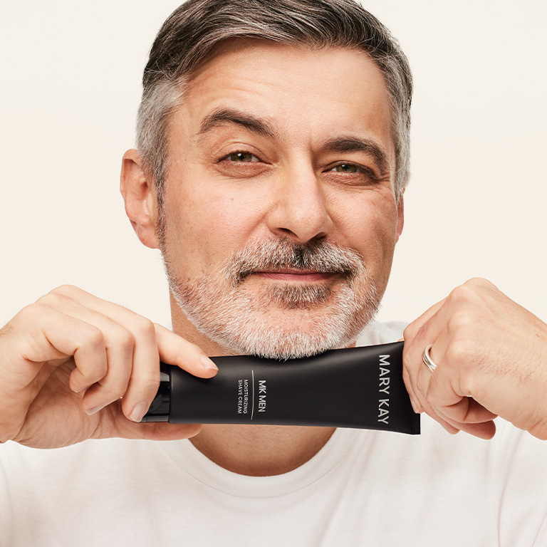Man smiling and holding a tube of Mary Kay MKMen Shave Cream up to his chin