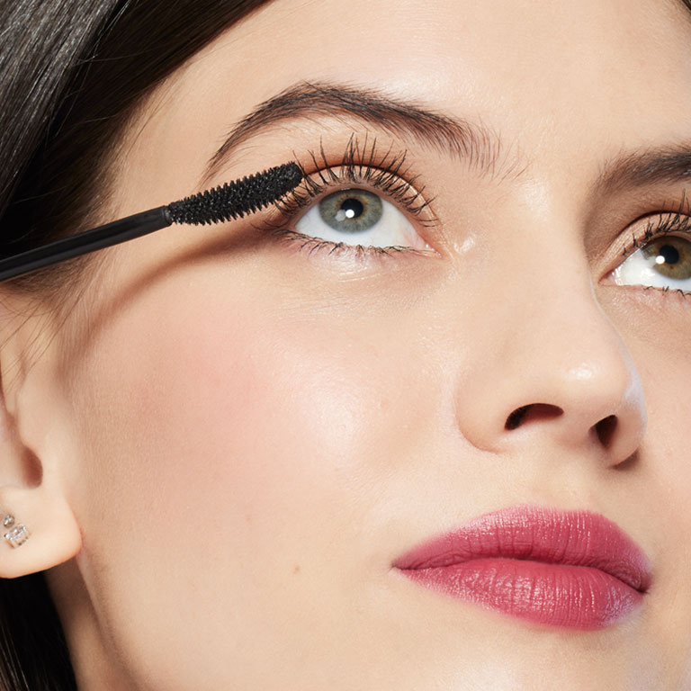 Modelo sosteniendo el aplicador de la M&aacute;scara para Pesta&ntilde;as Great Heights Mary Kay&reg; cerca del ojo.